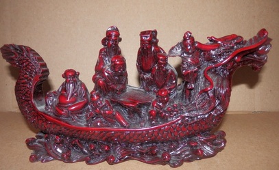 Red sculpture of 8 immortals sailing on a dragon boat