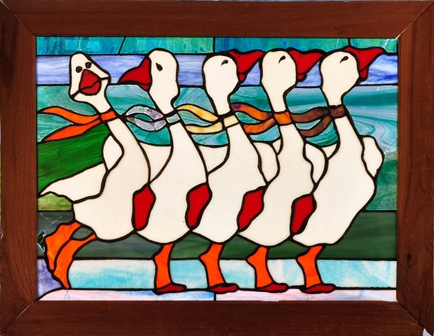 Stained glass window depicting five dancing geese