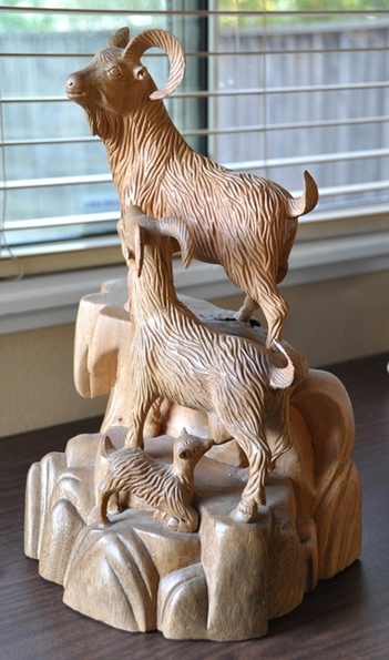Wood carved sculpture of a mountain goat family 