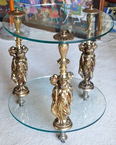 Mid-century Hollywood Regency glass end table with ornate figural posts