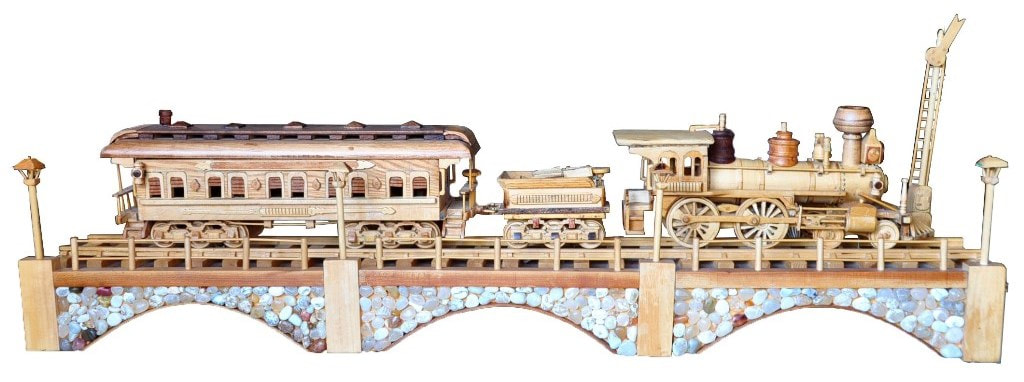Large wooden replica of the Iron Horse train with steam locomotive and wagon crossing a stone bridge