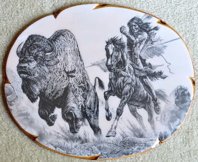 This is an etching by Montana artist Bill O'Neill titled Buffalo Hunt which shows a Native American on horse chasing a bison (buffalo).  It is mounted and laminated on an oval wood board of 19