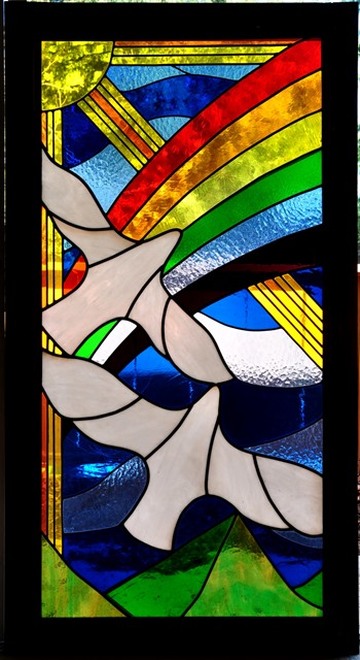 Large stained glass window with flying birds, rainbow and sun