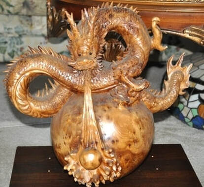 Carved wooden sculpture of a dragon siting on a ball