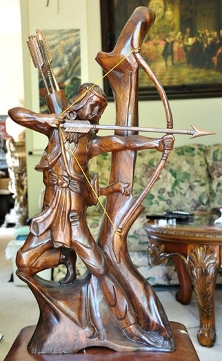 Wood carved sculpture of a Native American shooting an arrow from his bow