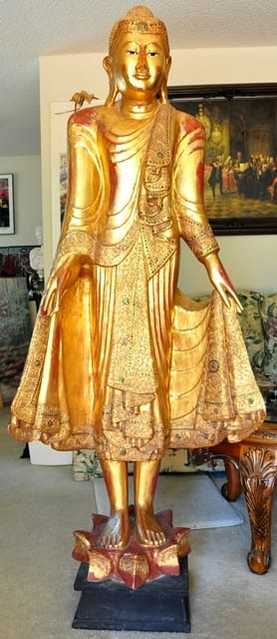 Large wooden standing Thai Buddha statue covered in gold leaf