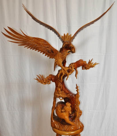 Large wooden sculpture of two eagles on top of a tree and a lion at the bottom